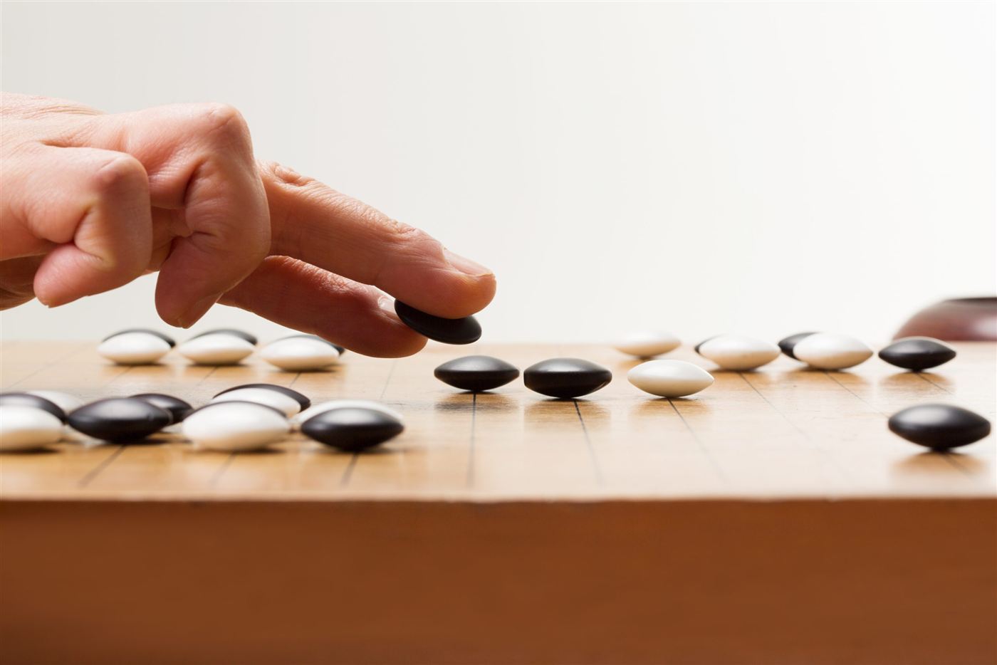 A hand placing a black Go stone