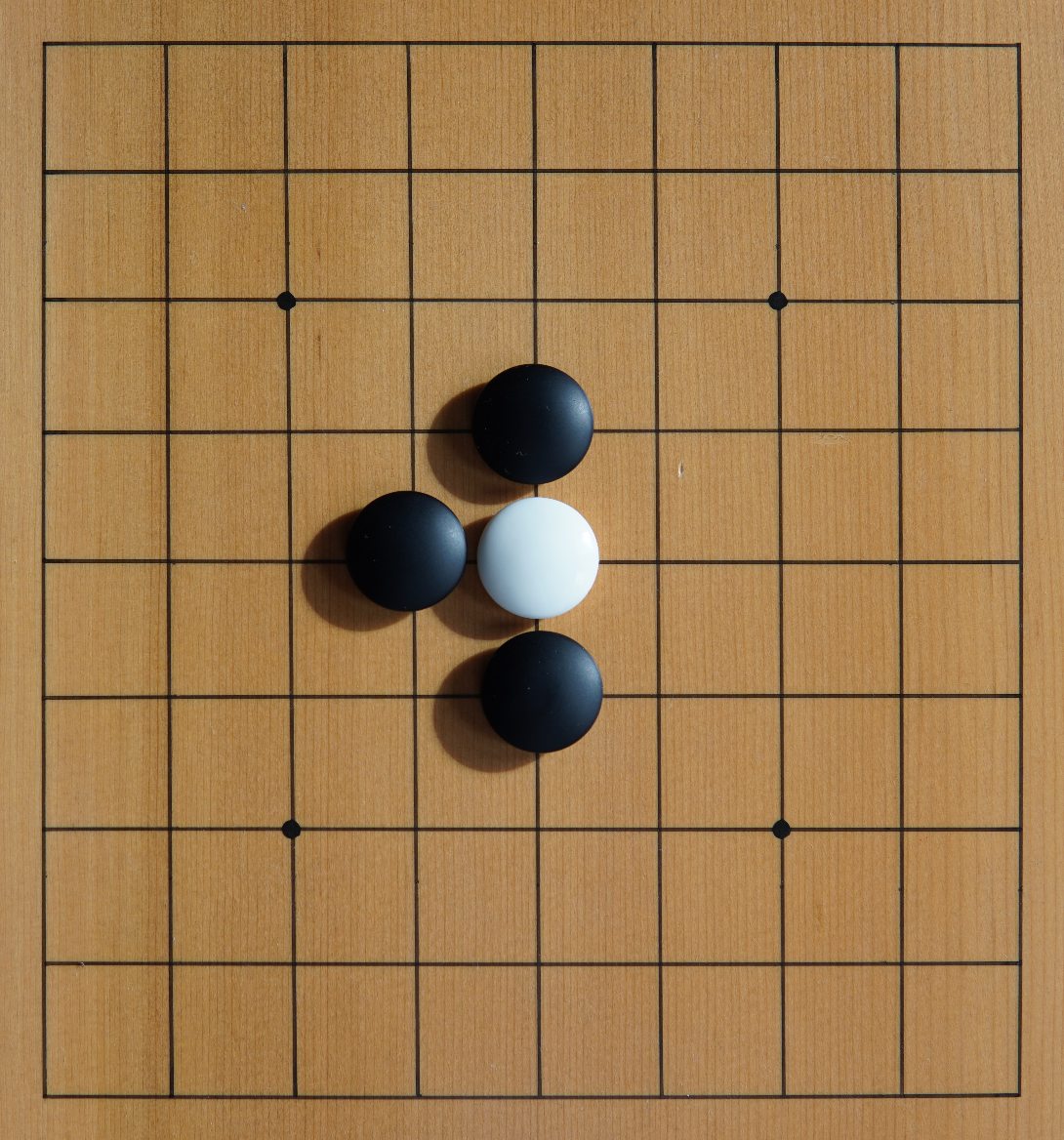 A white stone surrounded by three black stones, one liberty left